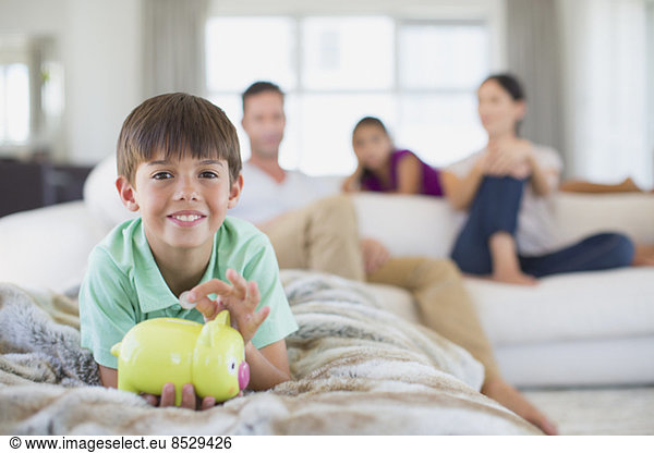 Boy with piggy bank on sofa in living room