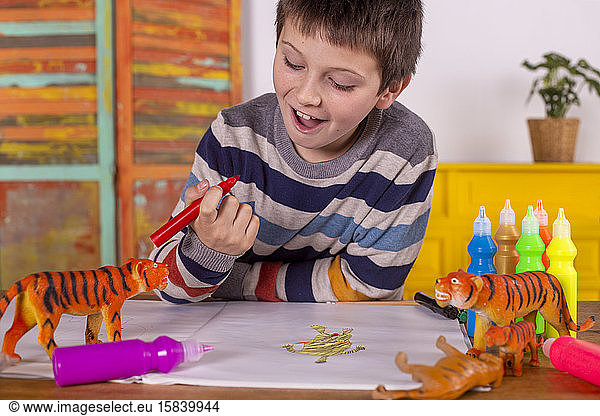 Boy with red marker pen painting a tiger