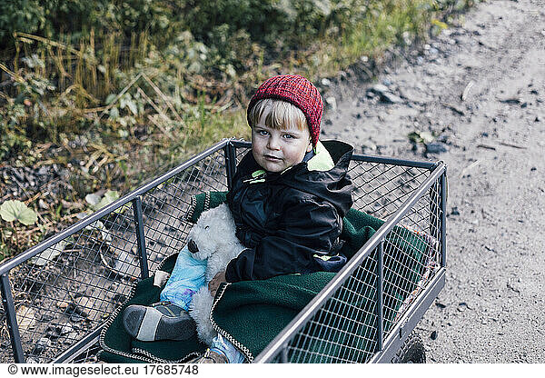 Boy with toy sitting in garden cart