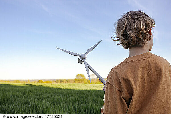 Boy with wind turbine model on field