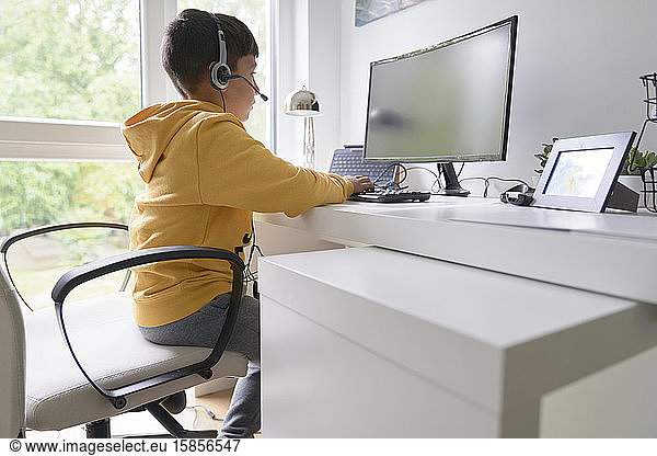 Boy with yellow t-shirt in the computer making homework