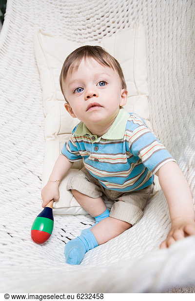 Boy  1 years  with rattle  sitting in a hammock