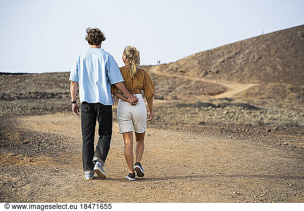 Boyfriend and girlfriend walking with each other on dirt road