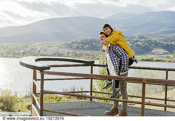 Boyfriend giving piggyback ride to girlfriend standing on observation point