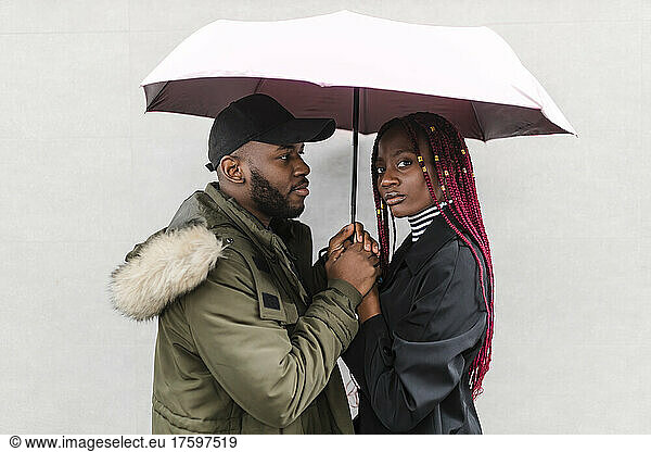 Boyfriend looking at girlfriend below umbrella