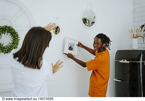 Boyfriend showing picture frame placing on wall at home
