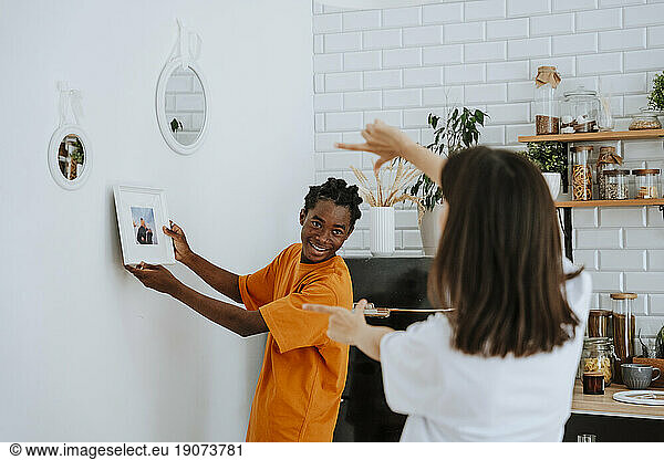 Boyfriend showing picture frame placing on wall at home