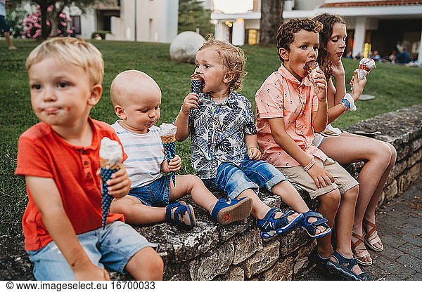 Boys and girls eating ice cream together during summer holidays