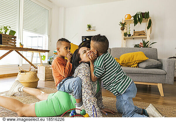 Boys playing with mother in living room at home