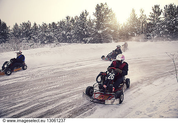 Boys racing on go-carts at snow covered field