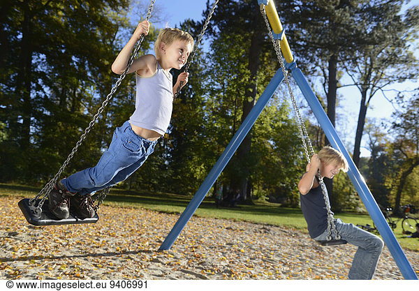 Boys swinging on swing in playground