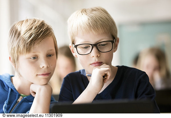 Boys using digital tablet for learning in classroom
