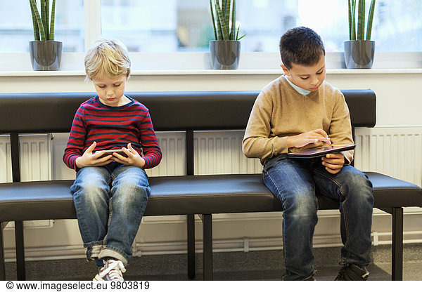 Boys using technologies while waiting at orthopedic clinic