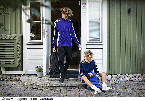 Brüder in Sportkleidung vor der Haustür