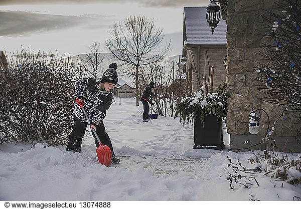 Brüder schaufeln Schnee vom Hinterhof