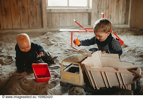 Brüder spielen mit Lastwagen und Schaufeln im Sandkasten im Winter