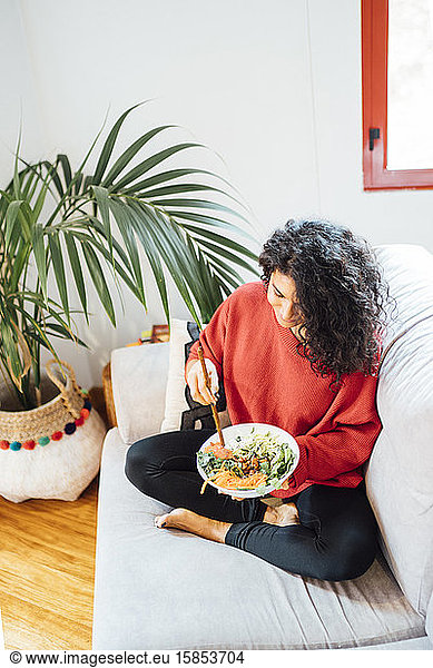 Brünette Frau isst einen gesunden grünen Salat.