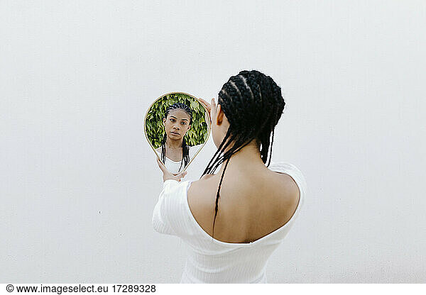 Braided hair woman looking at reflection in mirror