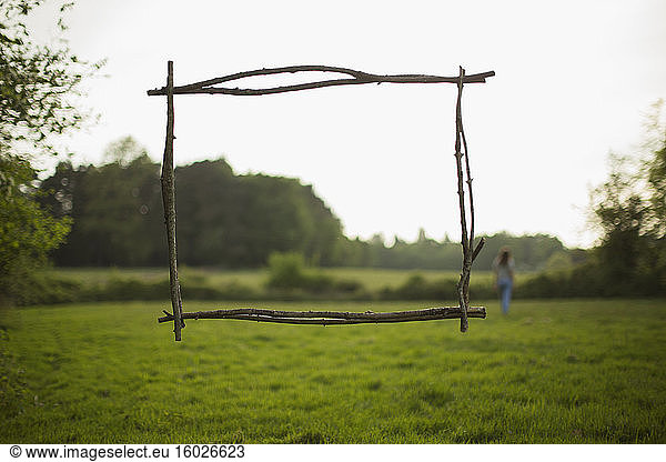 Branch frame over woman walking in idyllic grass field