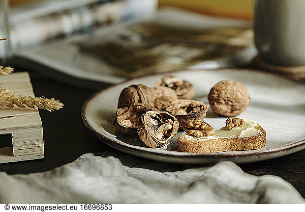 Bread toast with butter and open nuts on a plate in a cozy wood table