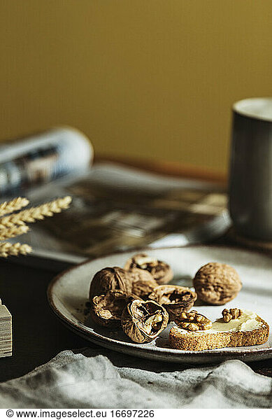Bread toast with butter and walnuts on a plate in a cozy wooden table