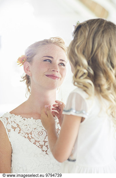 Bride and bridesmaid facing each other and smiling