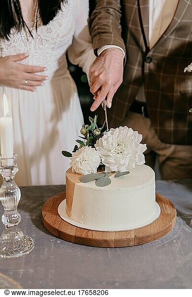 Bride and groom in wedding dresses cut the wedding cake