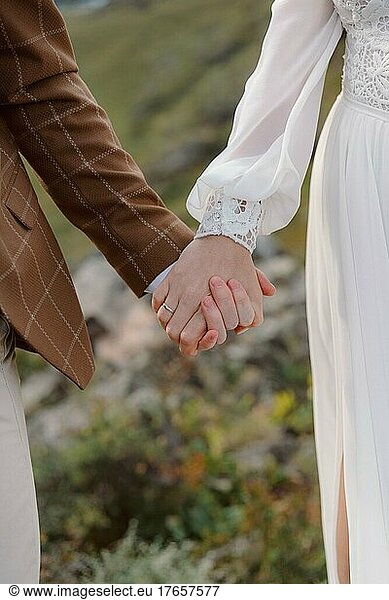 Bride and groom in wedding dresses hold hands