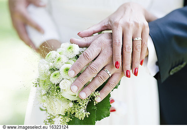 Bride and groom showing wedding rings  holding bouquet