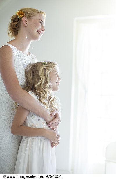 Bride embracing bridesmaid and looking out of window