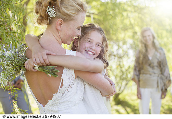 Bride embracing bridesmaid at wedding reception in domestic garden