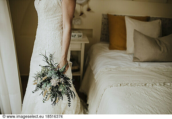 Bride holding bouquet of flowers in bedroom