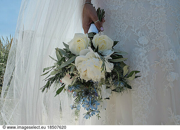bride standing in her lace wedding dress holding her bouque of flowers