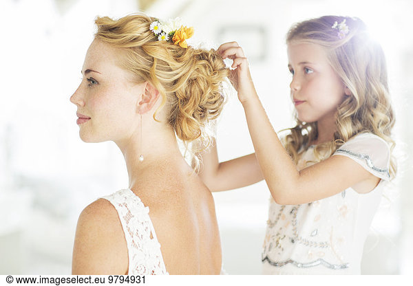 Bridesmaid helping bride with hairstyle in domestic room