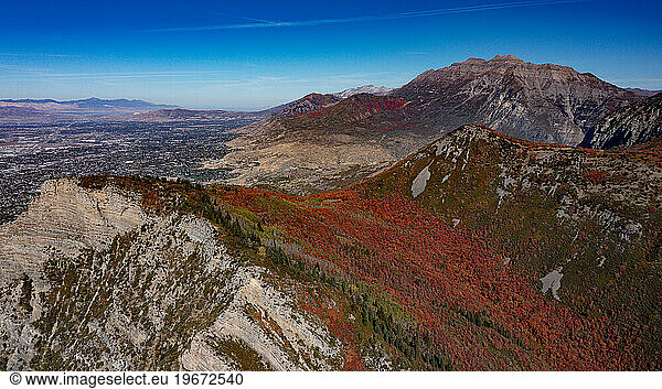 Bright red leaves on trees in mountain range in fall with blue sky