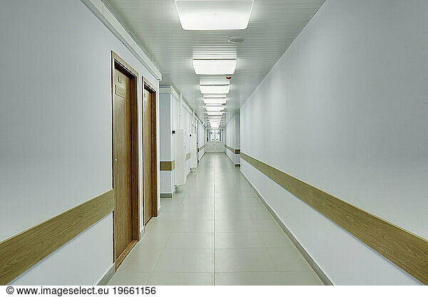 Brightly lit corridor in a sports hall with doors leading off it.