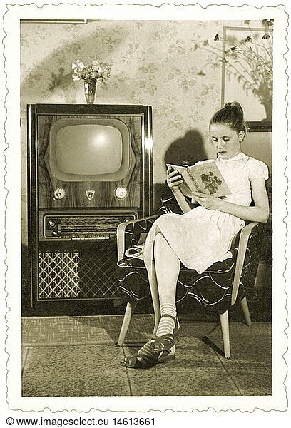broadcast  television  viewers  woman reading book  East Germany  1958  technic  technics  invention  GDR  historic  historical  1950s  model Clivia FER 858  produced by VEB Sachsenwerk Radeberg  first TV chest in GDR  43 cm screen diagonal  sitting in chair  models  sets  viewer  people  20th century  women  female