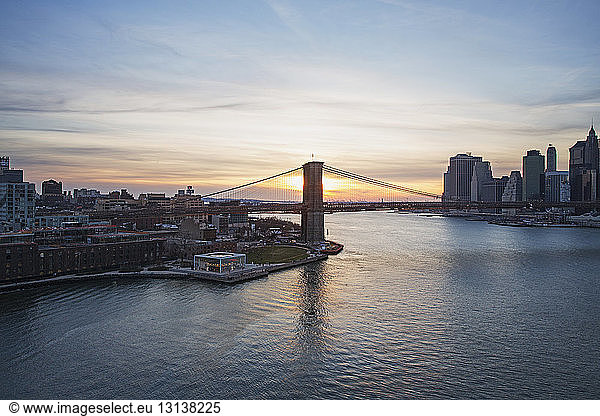 Brooklyn Bridge over East River against sky during sunset