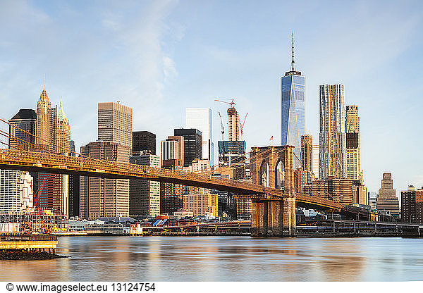 Brooklyn Bridge over East river against sky in New York city