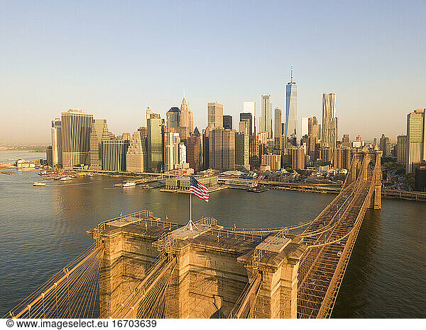 Brookyln Bridge Luftaufnahme mit wehender amerikanischer Flagge und Manhattan Skyline im Hintergrund im Tageslicht