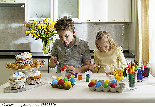 Brother and sister are painting Easter eggs.