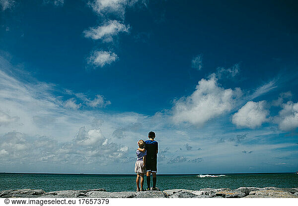 Brother and sister overlooking blue summer sky and ocean