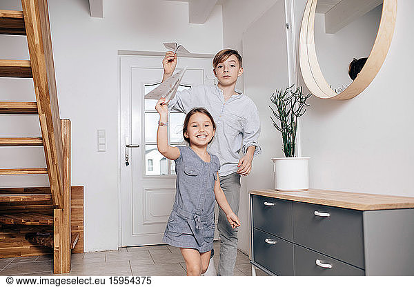 Brother and sister playing with paper planes