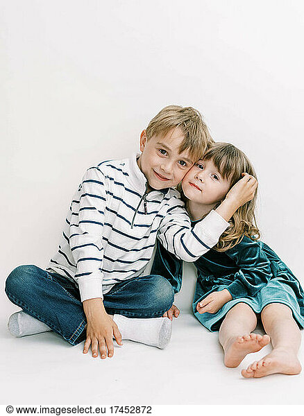 Brother and Sister posing on an off-white background