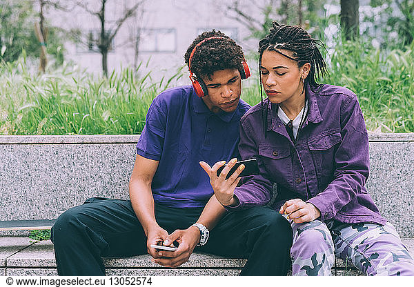 Brother and sister watching footage on mobile phone together  Milan  Italy