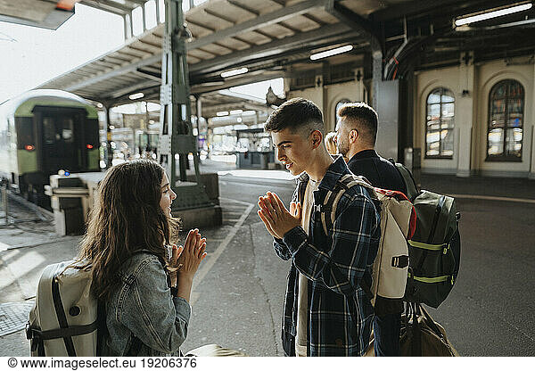 Brother playing leisure game with sister while waiting for train at railroad station
