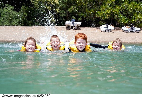 Brothers and sister in a row swimming in sea