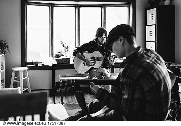 Brothers play guitar together indoors at home