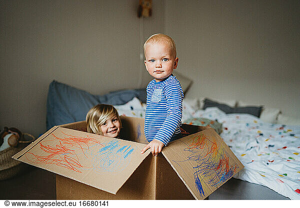 Brothers playing and drawing in a box during lockdown