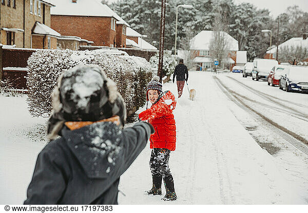Brothers throwing snowballs in residential street in snow